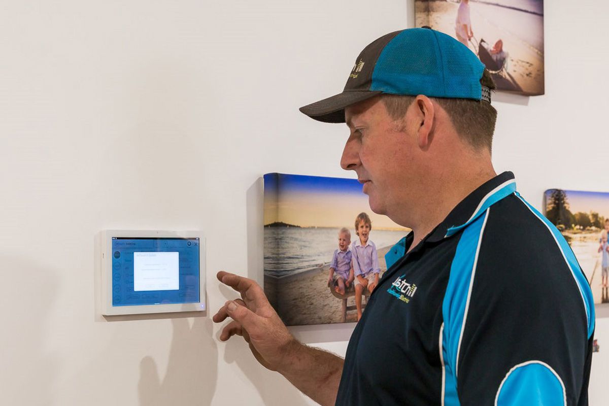 Brad adjusting a wall-mounted Air Touch air conditioning control panel.